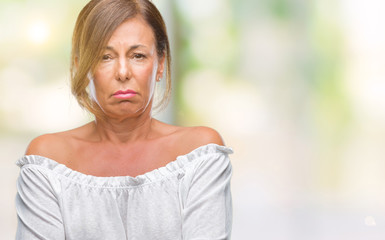 Middle age senior hispanic woman over isolated background skeptic and nervous, disapproving expression on face with crossed arms. Negative person.