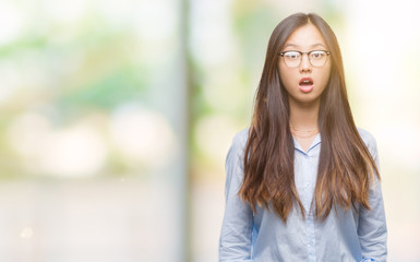 Young asian business woman wearing glasses over isolated background afraid and shocked with surprise expression, fear and excited face.