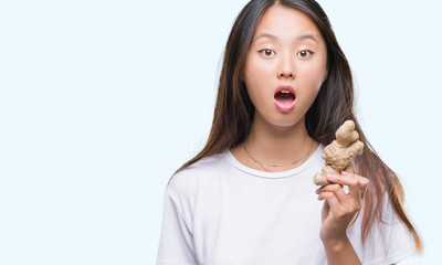 Young asian woman holding fresh organic over isolated background scared in shock with a surprise face, afraid and excited with fear expression