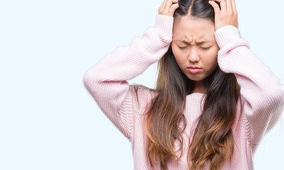 Young asian woman over isolated background suffering from headache desperate and stressed because pain and migraine. Hands on head.