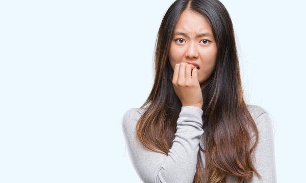 Young asian woman over isolated background looking stressed and nervous with hands on mouth biting nails. Anxiety problem.