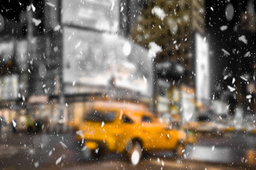 Defocused blur New York City midtown Manhattan street scene with yellow taxi cab and snowflakes falling during winter snow storm