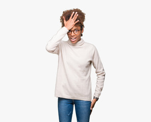 Beautiful young african american woman wearing glasses over isolated background surprised with hand on head for mistake, remember error. Forgot, bad memory concept.