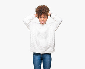 Beautiful young african american woman wearing winter sweater over isolated background Crazy and scared with hands on head, afraid and surprised of shock with open mouth