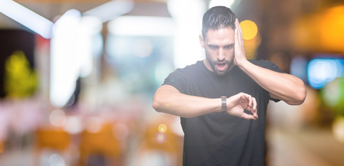 Young handsome man over isolated background Looking at the watch time worried, afraid of getting late