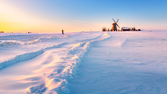 Wooden windmill on background winter sunrise. Dudutki village, Minsk Region, Belarus