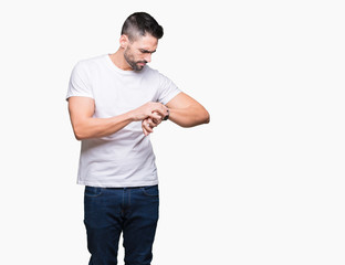 Handsome man wearing white t-shirt over white isolated background Checking the time on wrist watch,...