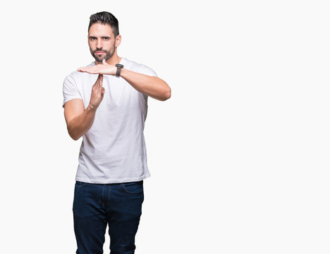 Handsome man wearing white t-shirt over white isolated background Doing time out gesture with hands, frustrated and serious face