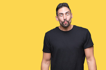 Young handsome man over isolated background making fish face with lips, crazy and comical gesture. Funny expression.