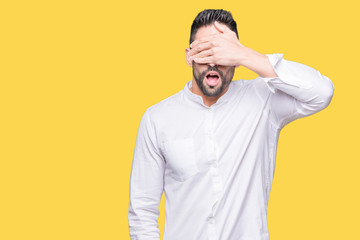 Young business man over isolated background smiling and laughing with hand on face covering eyes for surprise. Blind concept.