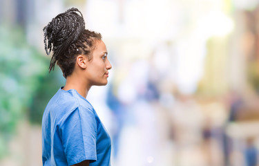 Young braided hair african american girl professional nurse over isolated background looking to side, relax profile pose with natural face with confident smile.