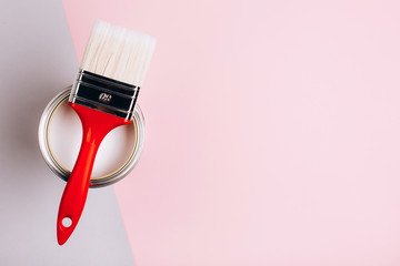 Brush with red handle on open can with pink color of paint on pastel background. Place for text....