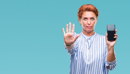 Atrractive senior caucasian redhead woman showing smartphone screen over isolated background with...