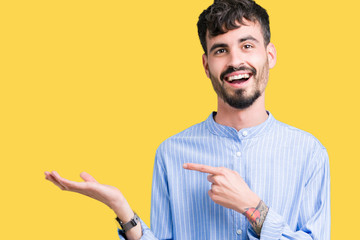 Young handsome business man over isolated background amazed and smiling to the camera while presenting with hand and pointing with finger.