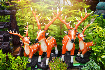 Statue of deer in the garden flowers / fake Orange deer cute With trees