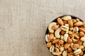 Roasted peanuts in the shell and peeled in a cup, against a gray wooden table