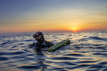 Female SCUBA diver on the surface of a tropical ocean at sunset