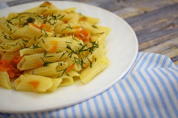 Delicious pasta with carrots and onions on wooden background.