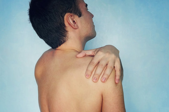 people, healthcare and problem concept - unhappy man suffering from neck or shoulder pain at home. cervical chondrosis arthrosis. fracture of the shoulder. usual dislocation of the shoulder