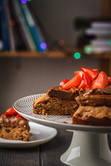 Vegan cake with dark chocolate, strawberries and chocolate cream on white dish, dark background.