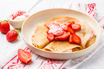 Crepes with strawberries and coconut cream, white background. Healthy vegan food concept.