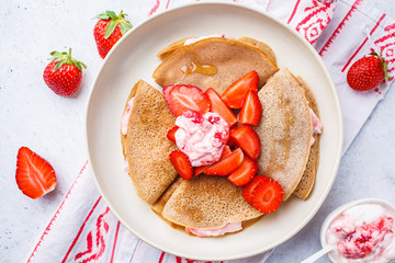 Crepes with strawberries and coconut cream, white background. Healthy vegan food concept.