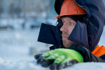 Portrait of an assembler in an orange helmet with a hood