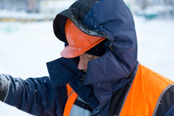 Portrait of an assembler in an orange helmet with a hood