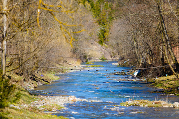 Suspension bridge hanging over mountain stream. Spring time. Ecological problem