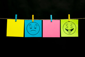 Copy space. Four stickers. On two sheets of smileys with the expression of emotions. Bewilderment. Love of money. Stickers are attached to the rope with clothespins.