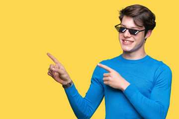Young man wearing funny thug life glasses over isolated background smiling and looking at the...