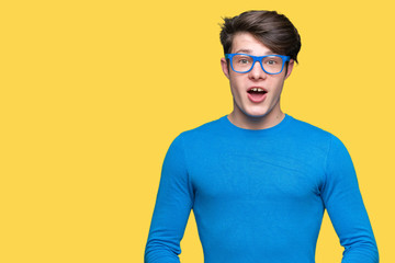 Young handsome man wearing blue glasses over isolated background afraid and shocked with surprise expression, fear and excited face.