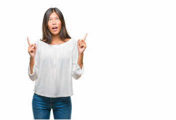 Young asian woman over isolated background amazed and surprised looking up and pointing with...