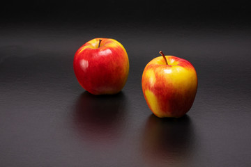 Two red and yellow Ambrosia apple on a black background with text space.