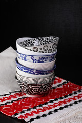 Stacked soup and cereal bowls on a hemp kitchen towl with a printed red and black pattern.  Text space.