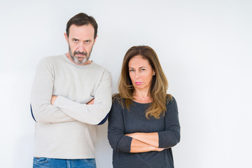 Beautiful middle age couple in love over isolated background skeptic and nervous, disapproving...