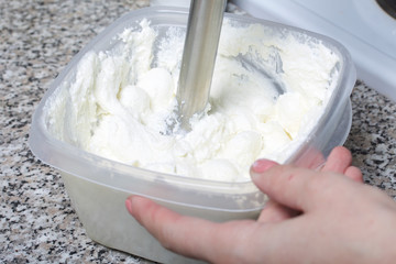 A woman blends a curd mass with a blender.