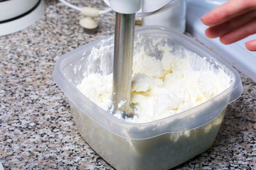 A woman blends a curd mass with a blender.