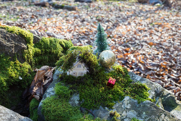 Christmas and New Year miniature house at forest in the sunlight. Little toy house close up. Festive background. Christmas decorations. Holiday and celebration concept.