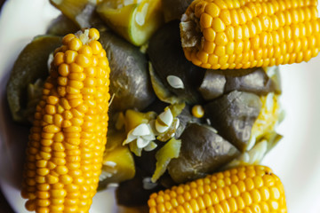 Close-up macro of boiled corn and vegetables on a white plate viewed from above