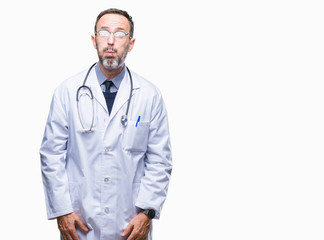 Middle age senior hoary doctor man wearing medical uniform isolated background puffing cheeks with funny face. Mouth inflated with air, crazy expression.