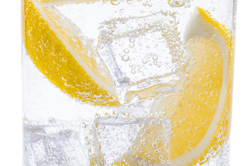 Slices of fresh juicy yellow lemon with ice in clear water.