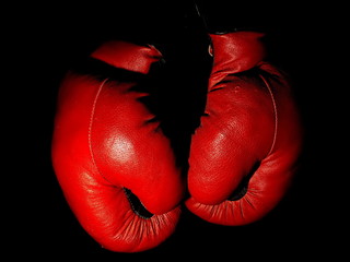 Old leather red boxing gloves hanging in the dark