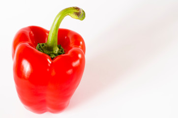 Juicy red Bulgarian pepper with a green tail lies on a white background