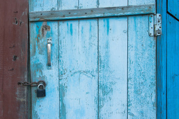 Old wooden blue door and rust padlock.