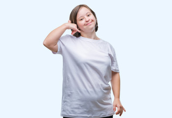 Young adult woman with down syndrome over isolated background smiling doing phone gesture with hand...