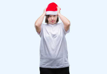 Young adult woman with down syndrome wearing christmas hat over isolated background suffering from headache desperate and stressed because pain and migraine. Hands on head.