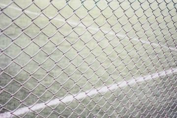 Tennis court fencing with mesh netting against the background of the court and marking with white paint overlay texture