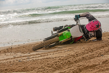 motorcyclist fell on a motorcycle on the beach against the backdrop of the sea