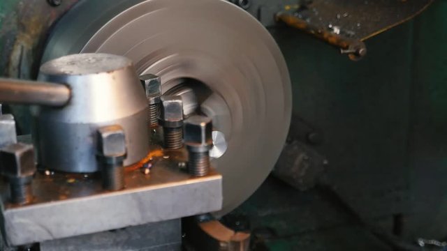 Chisel cutting chips from a metallic rod fixed to a lathe cylinder on workshop 